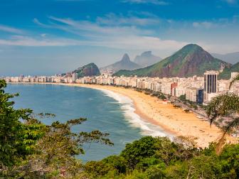 Photo of Copacabana Beach, the ocean and the cityscape of Rio de Janeiro, during summer in Brazil.